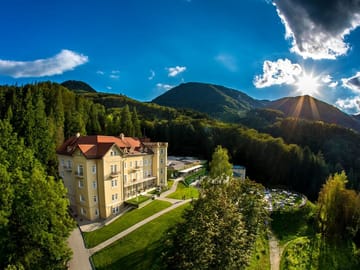 Luxuriöses Hotel inmitten einer waldreichen Berglandschaft bei Sonnenuntergang