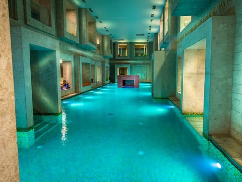 Luxuriöses Hallenbad mit modernen architektonischen Details und stimmungsvoller Beleuchtung.