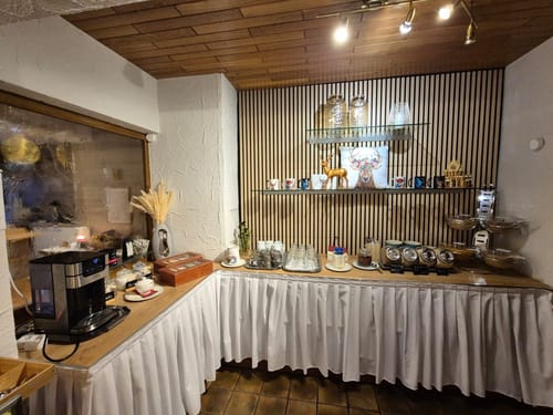 Frühstücksbuffet mit Kaffeemaschine und Auswahl an Beilagen in einem gemütlichen Restaurant.