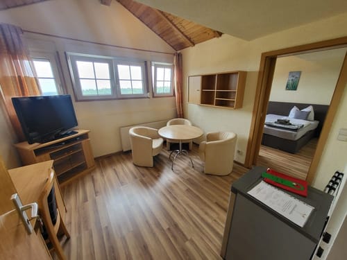 Gemütliches Wohnzimmer in einer Ferienwohnung mit Sitzbereich, Fernseher und Zugang zum Schlafzimmer