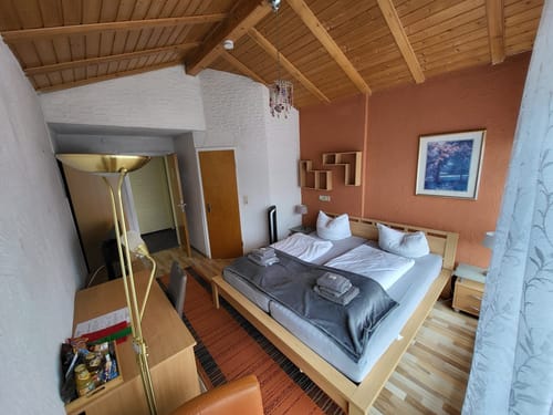 Gemütliches Hotelzimmer mit Doppelbett, Schreibtisch und Lampe, dekoriert in warmen Farben.