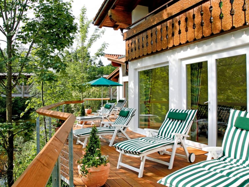 Sonnenterrasse mit bequemen Liegestühlen und grüner Umgebung in einem alpinen Hotel.