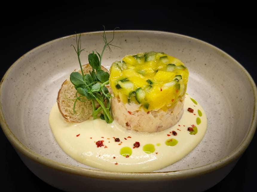Gourmet-Vorspeise mit Krabben-Tatar, Mango-Gurke-Garnitur und Sahnesauce.