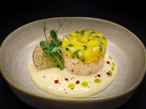Gourmet-Vorspeise mit Krabben-Tatar, Mango-Gurke-Garnitur und Sahnesauce.