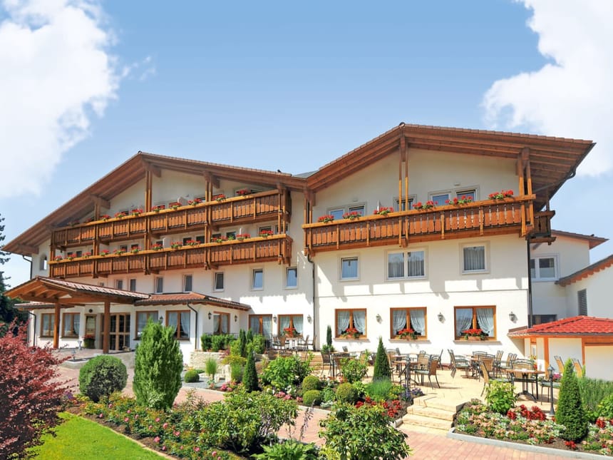 Traditionelles bayerisches Hotelgebäude mit gepflegtem Garten und Balkonen