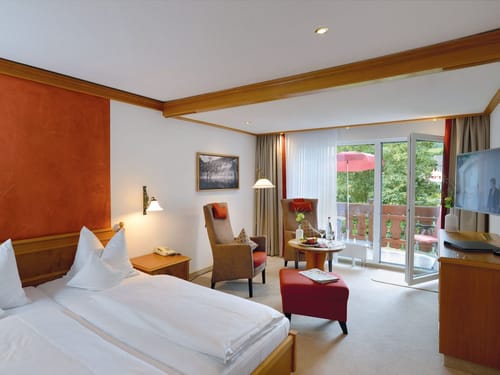 Gemütliches Hotelzimmer mit Doppelbett, Sitzbereich und Balkon