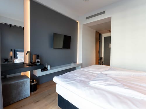 Modernes Hotelzimmer mit Doppelbett, Flachbildfernseher und Kaffeemaschine.