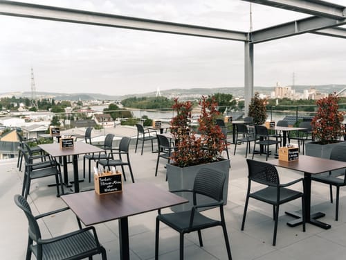 Dachterrasse mit Tischen und Stühlen mit Blick über eine Stadt
