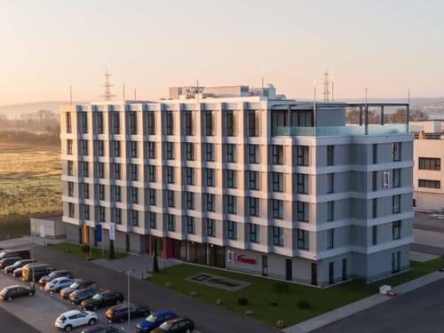 Modernes Geschäftsgebäude bei Sonnenuntergang mit Parkplatz im Vordergrund.