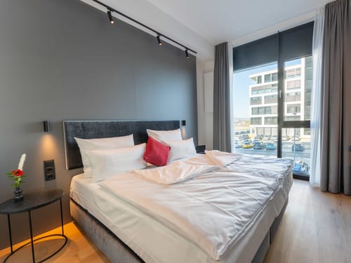 Modernes Hotelzimmer mit Doppelbett, elegantem Design und großer Fensterfront.