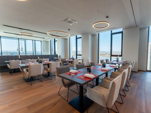 Entdecken Sie das elegante Ambiente eines modernen Restaurants mit Panoramafenstern, das stilvolles Design und einladende Sitzbereiche bietet. Perfekt für besondere Anlässe und kulinarische Erlebnisse.