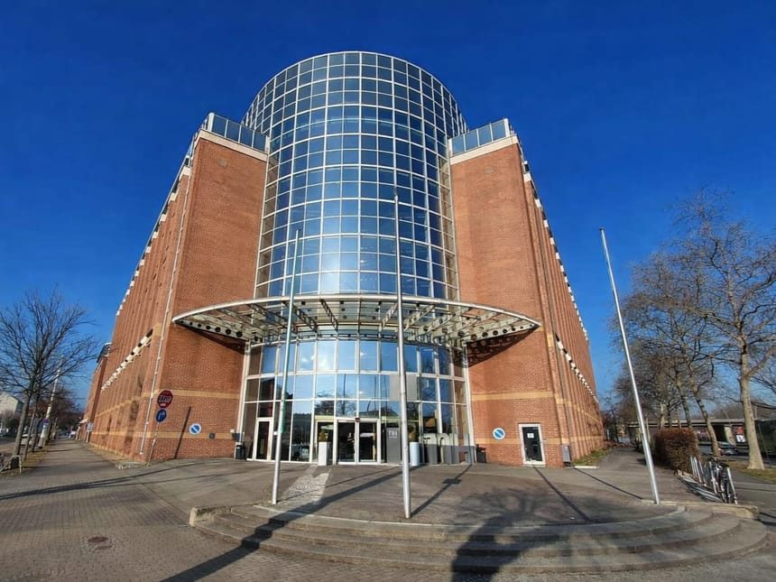 Modernes Backsteingebäude mit Glasfassade bei blauem Himmel