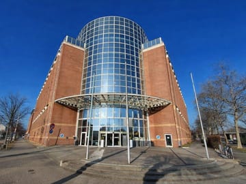 Modernes Backsteingebäude mit Glasfassade bei blauem Himmel