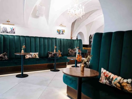 Elegantes Café-Interieur mit grünen Samtsitzbänken und kunstvollen Dekorationen.