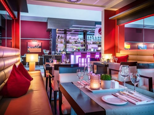 Modern eingerichtetes Restaurant mit stilvoller Beleuchtung und Bar im Hintergrund.
