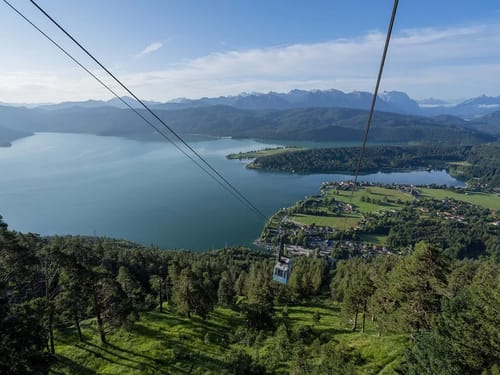 Seilbahn über einen alpinen See mit beeindruckender Berglandschaft im Hintergrund.