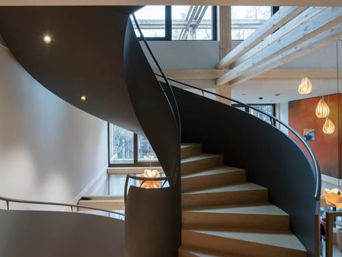 Moderne Wendeltreppe in einem stilvollen Interieur mit Holz- und Glaselementen.