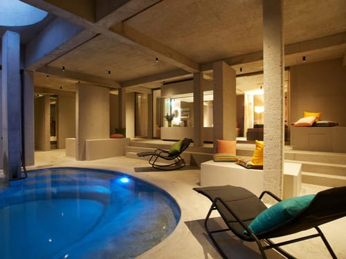 Moderner Indoor-Poolbereich mit stilvollen Möbeln und Beleuchtung.