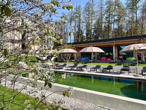 Moderner Wellnessbereich mit Pool und Liegestühlen im Grünen