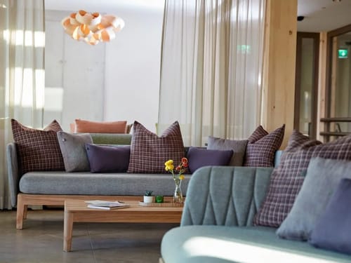 Elegantes Wohnzimmer mit modernen Sofas und dekorativen Kissen, umgeben von sanften Lichtakzenten.