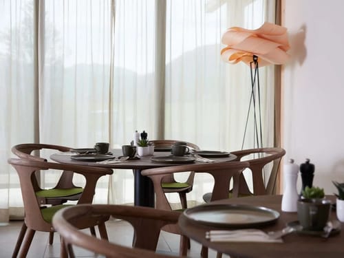 Modern eingerichtetes Café mit Holzstühlen und elegant gedecktem Tisch vor einem großen Fenster