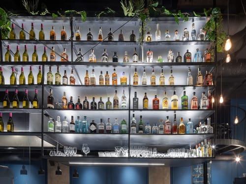 Große Spirituosenauswahl in beleuchteter Bar – Whisky, Gin und mehr