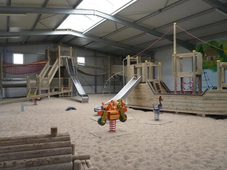 Indoor-Spielplatz mit Holzspielgeräten und Rutschen