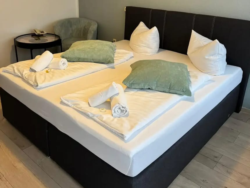 Elegantes Doppelbett in einem modernen Hotelzimmer mit frischen Handtüchern und Kissen.