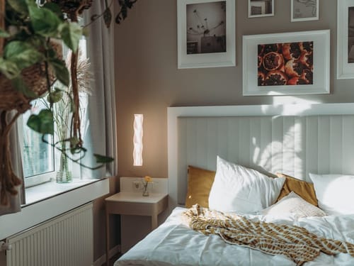 Gemütliches Schlafzimmer mit Kunstwerken und grünen Pflanzen