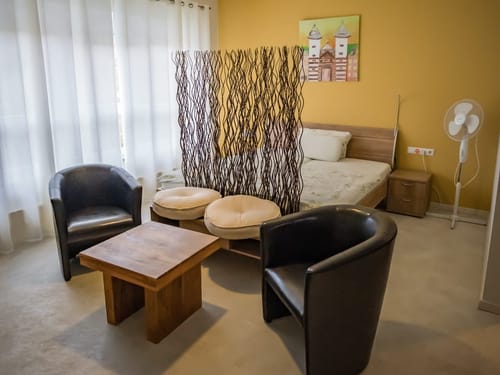 Elegantes Gästezimmer mit modernen Möbeln, Raumtrenner und gemütlicher Sitzecke.