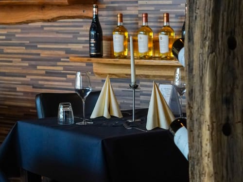 Elegantes Restaurant mit gedecktem Tisch und Weinflaschen im Hintergrund