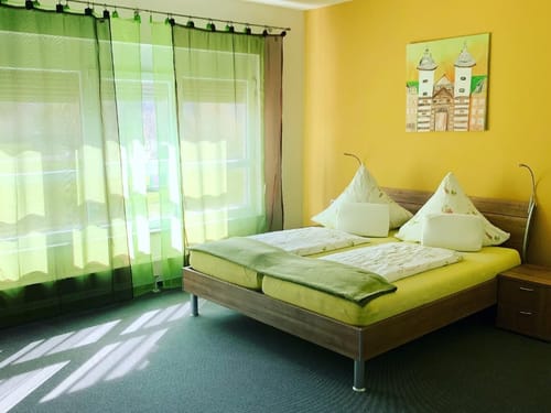 Modernes Schlafzimmer mit gelben Wänden und großen, grünen Vorhängen
