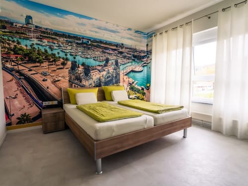 Modern eingerichtetes Schlafzimmer mit großem Fototapeten-Motiv einer Hafenstadt.