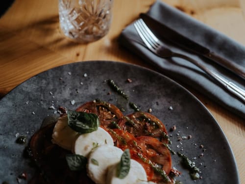 Italienisches Caprese-Salatgericht mit Mozzarella, Tomaten und Basilikum auf einem dunklen Teller