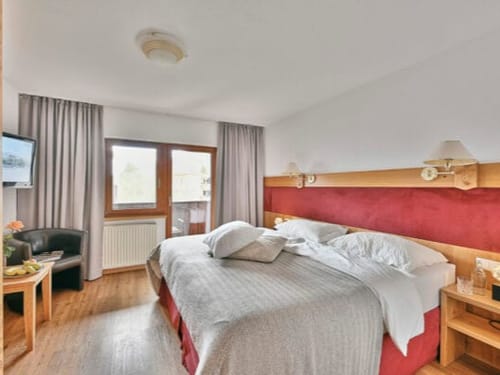Gemütliches Hotelzimmer mit Doppelbett, modernem Interieur und Balkonblick.