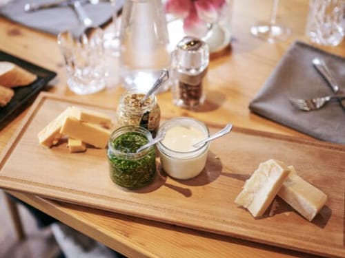 Käseplatte mit verschiedenen Saucen und Brot auf einem Holztisch