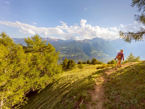 Wanderer auf Bergpfad mit Blick auf malerische Alpenlandschaft