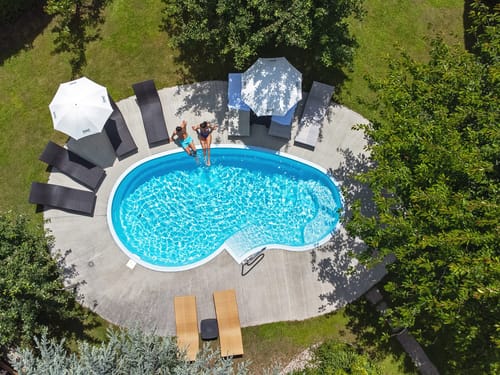 Luftaufnahme eines Swimmingpools im Garten mit Sonnenliegen und Sonnenschirmen