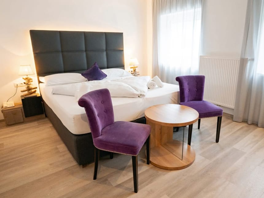 Gemütliches Hotelzimmer mit elegantem Doppelbett und lila Akzenten