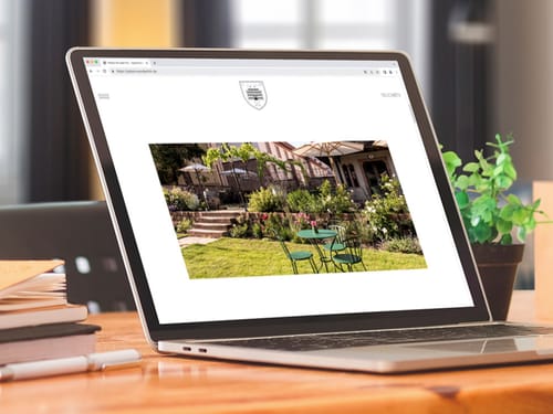 Laptop auf einem Schreibtisch mit angezeigter Webseite eines Gartencafés