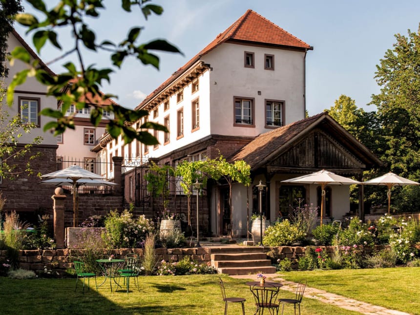 Traditionelles Fachwerkhaus mit Garten und Sonnenschirmen an einem sonnigen Tag