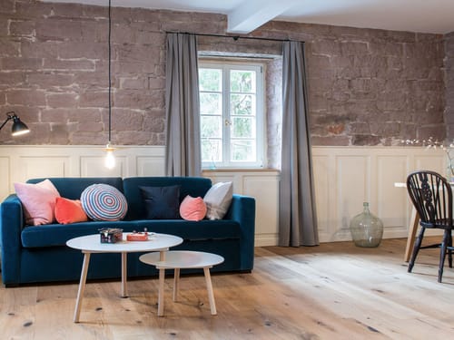 Stilvolles Wohnzimmer mit blauer Couch und gemischten Kissen, Holzboden und Steinwand