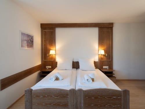 Entdecken Sie den Komfort dieses Hotelzimmers mit einem bequemen Doppelbett, warmer Beleuchtung und stilvoller Holzverkleidung. Ideal für Ihren nächsten erholsamen Aufenthalt.