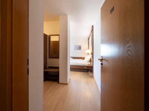 Blick in ein modernes Hotelzimmer mit Doppelbett und Holzmöbeln.