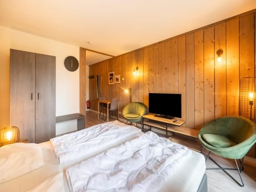 Gemütliches Hotelzimmer mit Doppelbett, Holzverkleidung und modernen Möbeln