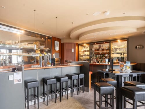Moderne Bar mit stilvollen Barhockern und gut bestücktem Getränkeregal.