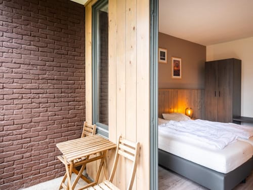 Gemütliches Schlafzimmer mit kleinem Balkon, Holzwänden und Ziegelsteindetail