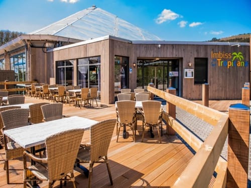 Außenterrasse des Imbiss Tropicana mit Korbmöbeln bei sonnigem Wetter