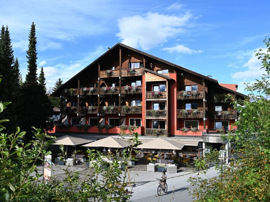 Traditionelles Alpenhotel mit blumengeschmückten Holzbalkonen und gemütlicher Außenterrasse