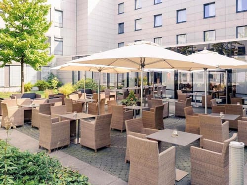 Gemütliche Außenterrasse eines Hotels mit Rattanstühlen und Sonnenschirmen